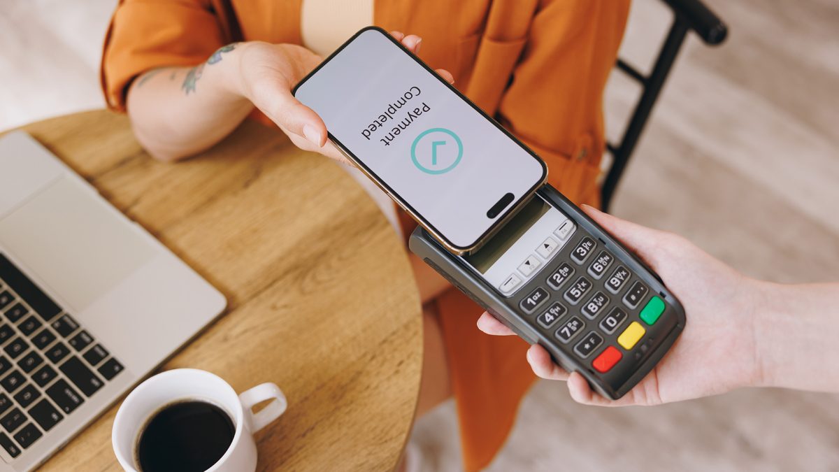 Persona realizando un pago sin contacto con su celular en una terminal